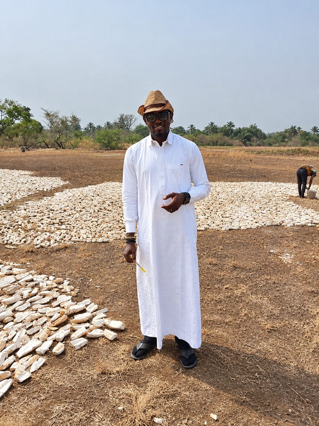 Standing in the field among cassava chips laid out to dry in the sun